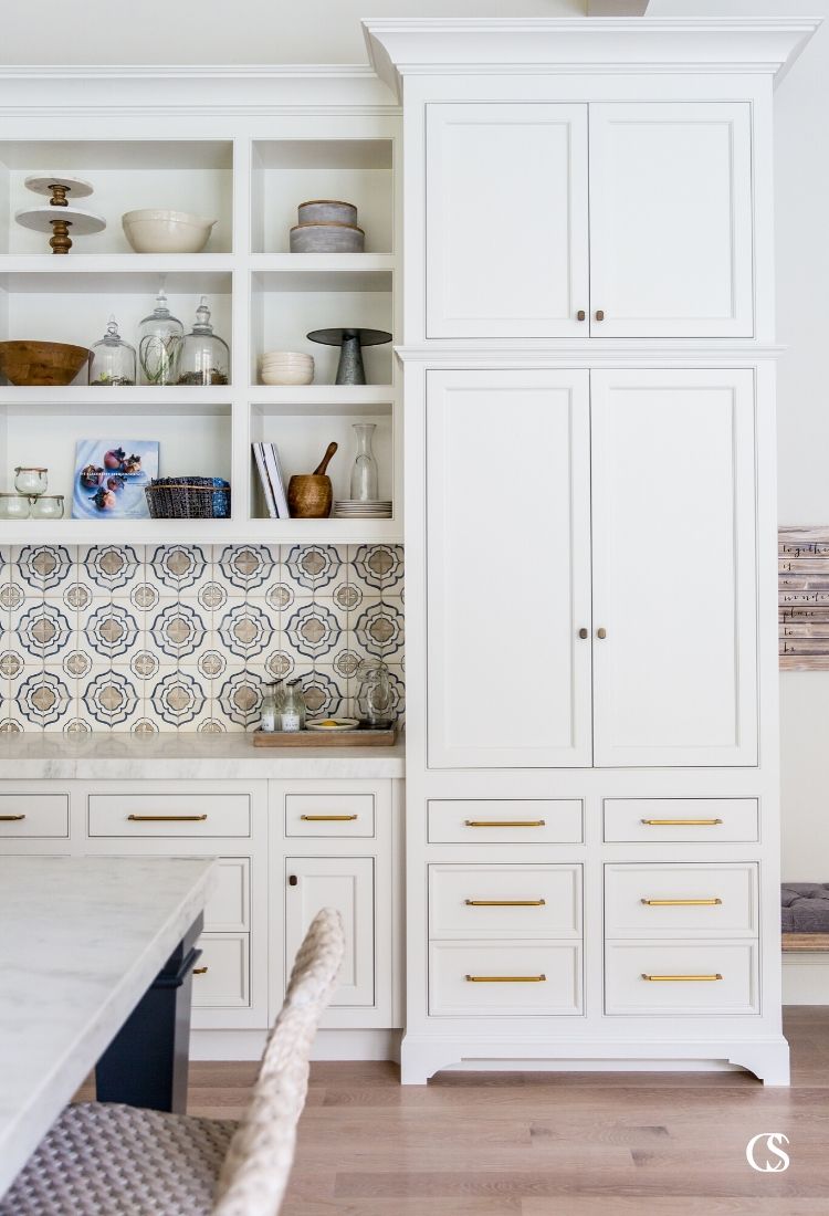 We love the mix of hardware styles mixed with a detailed tile backsplash in this set of custom cabinets for the kitchen and an open concept living room.