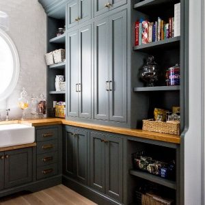 This kitchen pantry design included custom black cabinets, brass hardware, and oak countertops with plenty of space for style and storage.