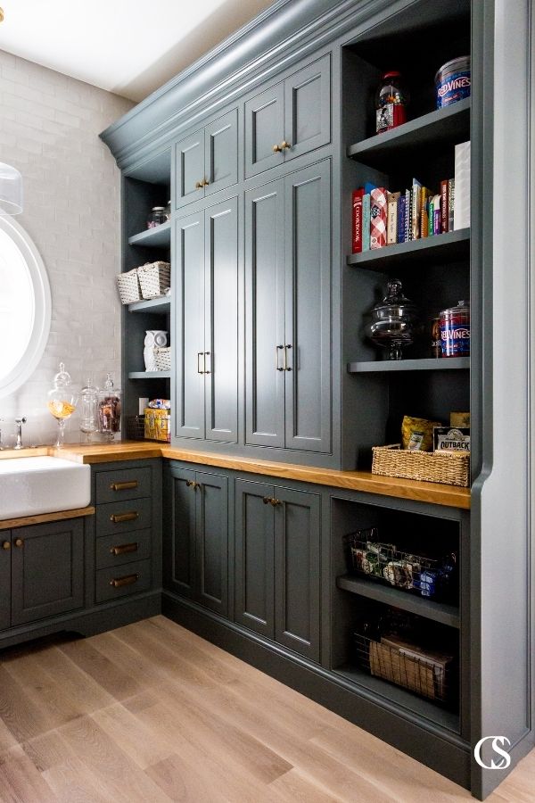 This kitchen pantry design included custom black cabinets, brass hardware, and oak countertops with plenty of space for style and storage.