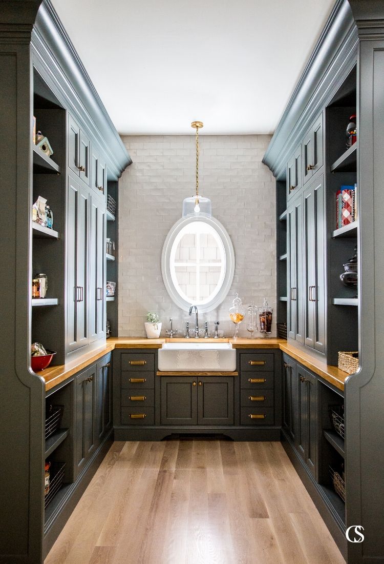 This pantry design included custom black cabinets, brass hardware, and oak countertops with plenty of space for style and storage.