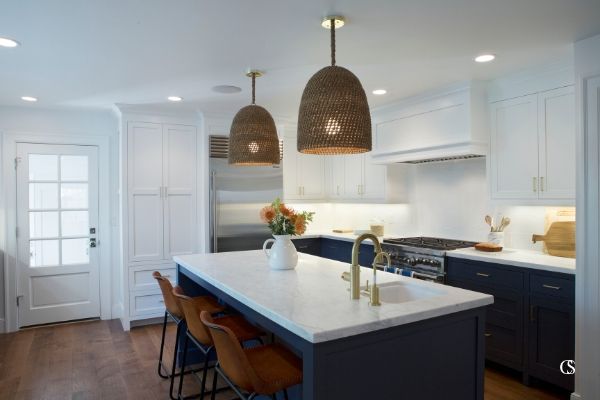 Hale Navy—a favorite blue paint for the kitchen—on these lower kitchen cabinets still looks bright and inviting when paired with the white upper cabinets and warm wood flooring here.