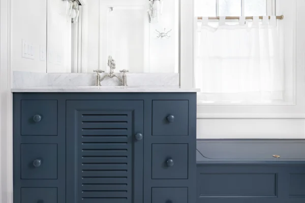 Meanwhile, the truer blue found on the colonial-style bathroom vanity embraces its purity with identically painted knobs, complemented by polished chrome fixtures' bright, clean look