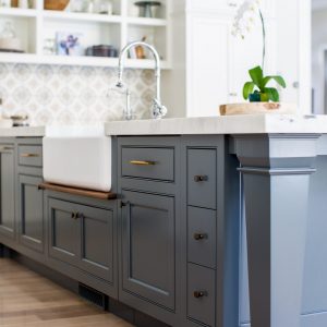 It's amazing how some open kitchen shelves can balance the weight of this blue kitchen island design. It almost creates an anchor for the room so great kitchen lighting and custom wall tile can really pop.