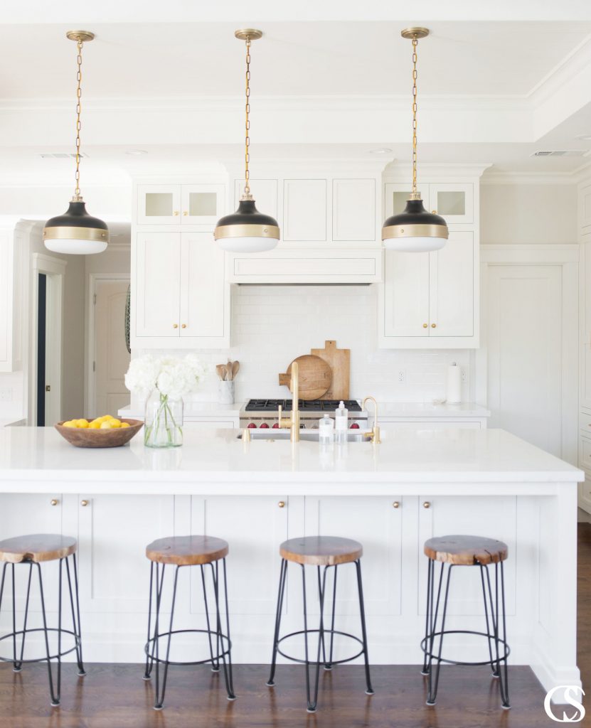 One of the great things about custom white kitchen cabinets is that they can hide more than you might think. Like this custom kitchen island for example—the perfect shade of white paint for the kitchen helps disguise extra storage in front of bar stools.