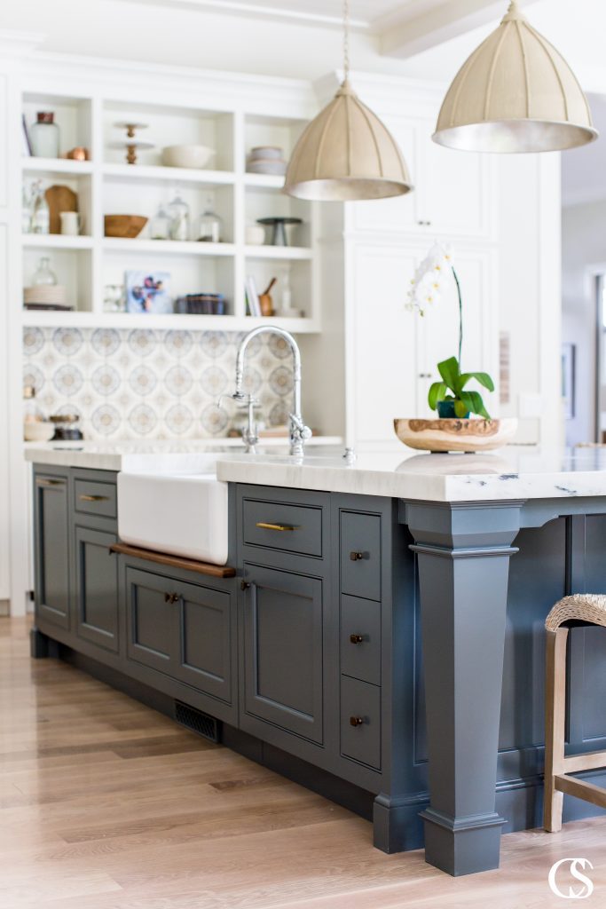It's amazing how some open kitchen shelves can balance the weight of this blue kitchen island design. It almost creates an anchor for the room so great kitchen lighting and custom wall tile can really pop.