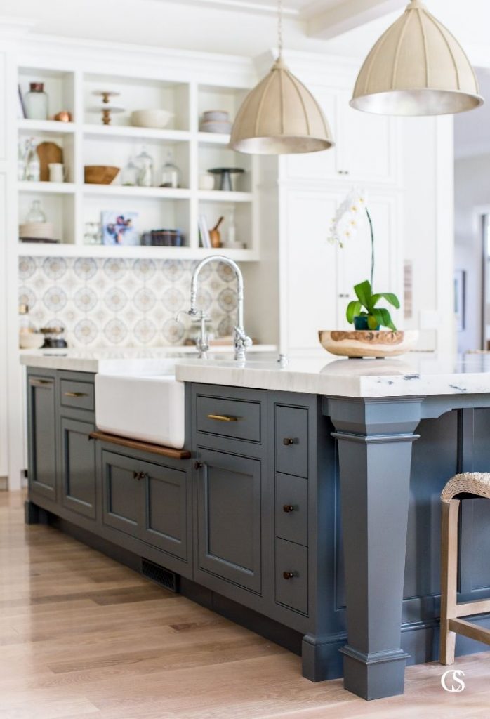 It's amazing how some open kitchen shelves can balance the weight of this blue kitchen island design. It almost creates an anchor for the room so great kitchen lighting and custom wall tile can really pop.