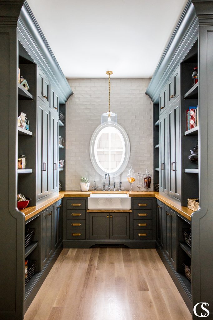 This pantry design included custom black cabinets, brass hardware, and oak countertops with plenty of space for style and storage.