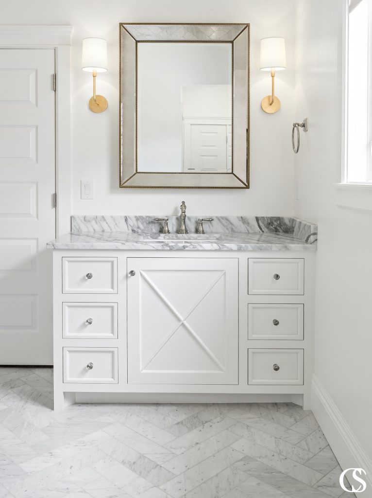 The best custom bathroom cabinet design can combine multiple aesthetics, like the modern and farmhouse looks you see coming together in this white bathroom vanity.