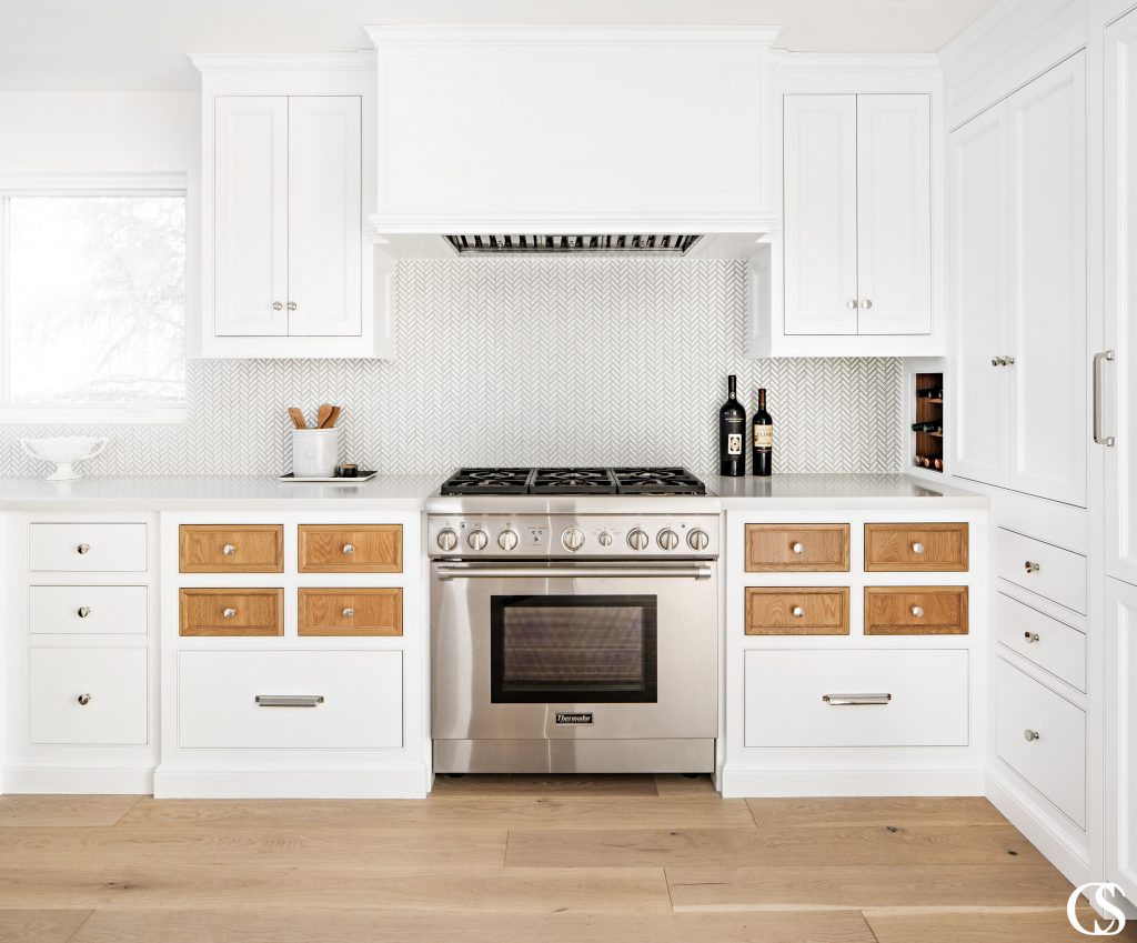 Who says every drawer and cupboard door have to match? These kitchen cabinet doors feature contrasting stained wood against the rest of the white painted cabinets, to great effect!
