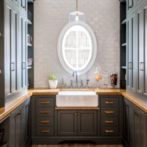 This custom pantry design included moody black cabinets, brass hardware, and oak countertops with plenty of space for style and storage.