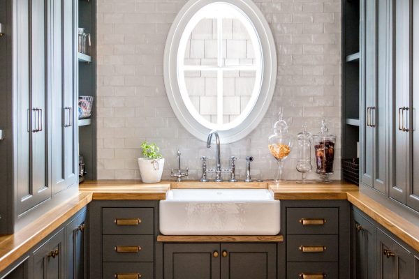 This custom pantry design included moody black cabinets, brass hardware, and oak countertops with plenty of space for style and storage.