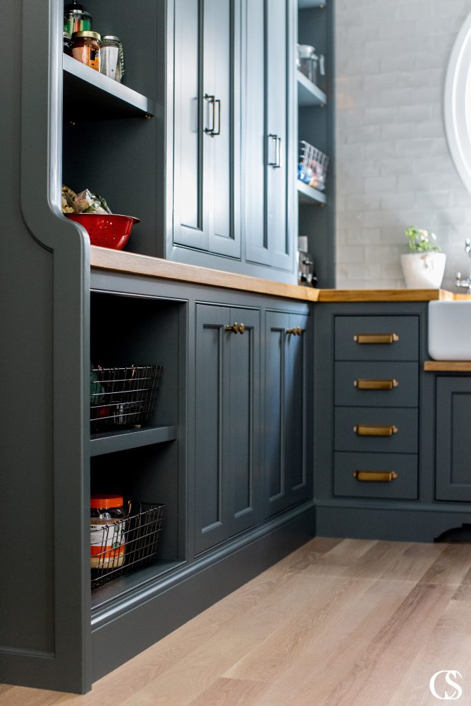 This custom kitchen pantry design idea included moody black cabinets, brass hardware, and oak countertops with plenty of space for style and storage.