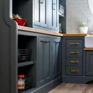 This custom kitchen pantry design idea included moody black cabinets, brass hardware, and oak countertops with plenty of space for style and storage.