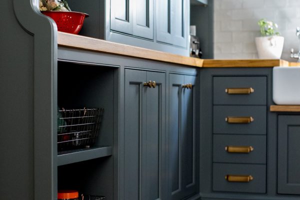 This custom kitchen pantry design idea included moody black cabinets, brass hardware, and oak countertops with plenty of space for style and storage.