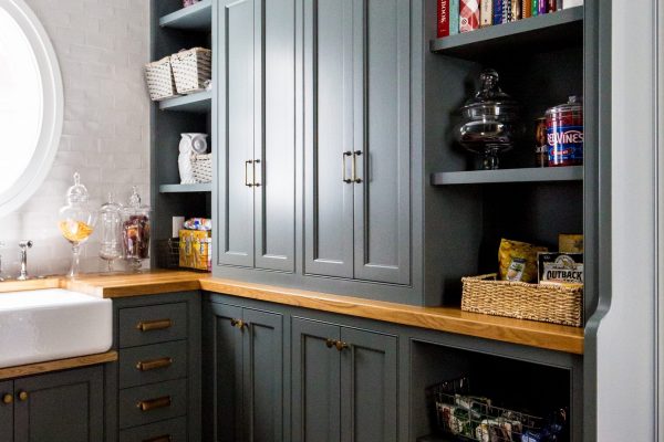 This kitchen pantry design included custom black cabinets, brass hardware, and oak countertops with plenty of space for style and storage.