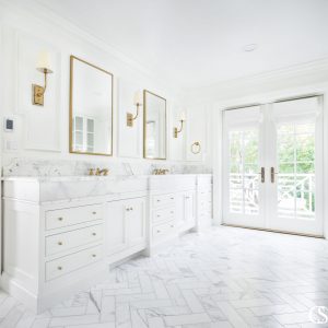 White inset cabinetry with white marble countertops, white herringbone floors, and white paint ensure that this white custom bathroom design excludes luxury.